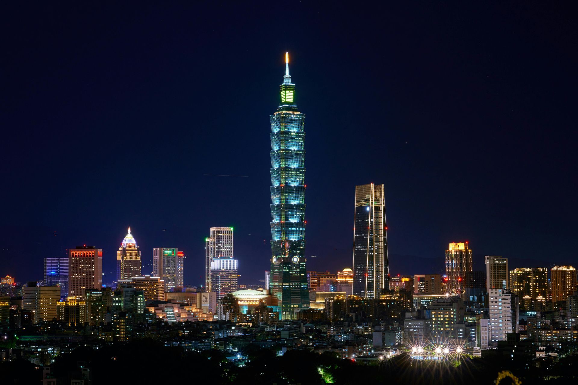 夜幕降臨，台北101大樓在漆黑的夜空中閃耀著藍色的光芒。