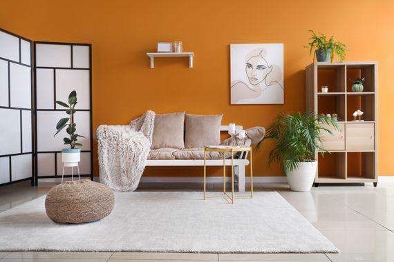 A living room with orange walls , a couch , a table and a rug.