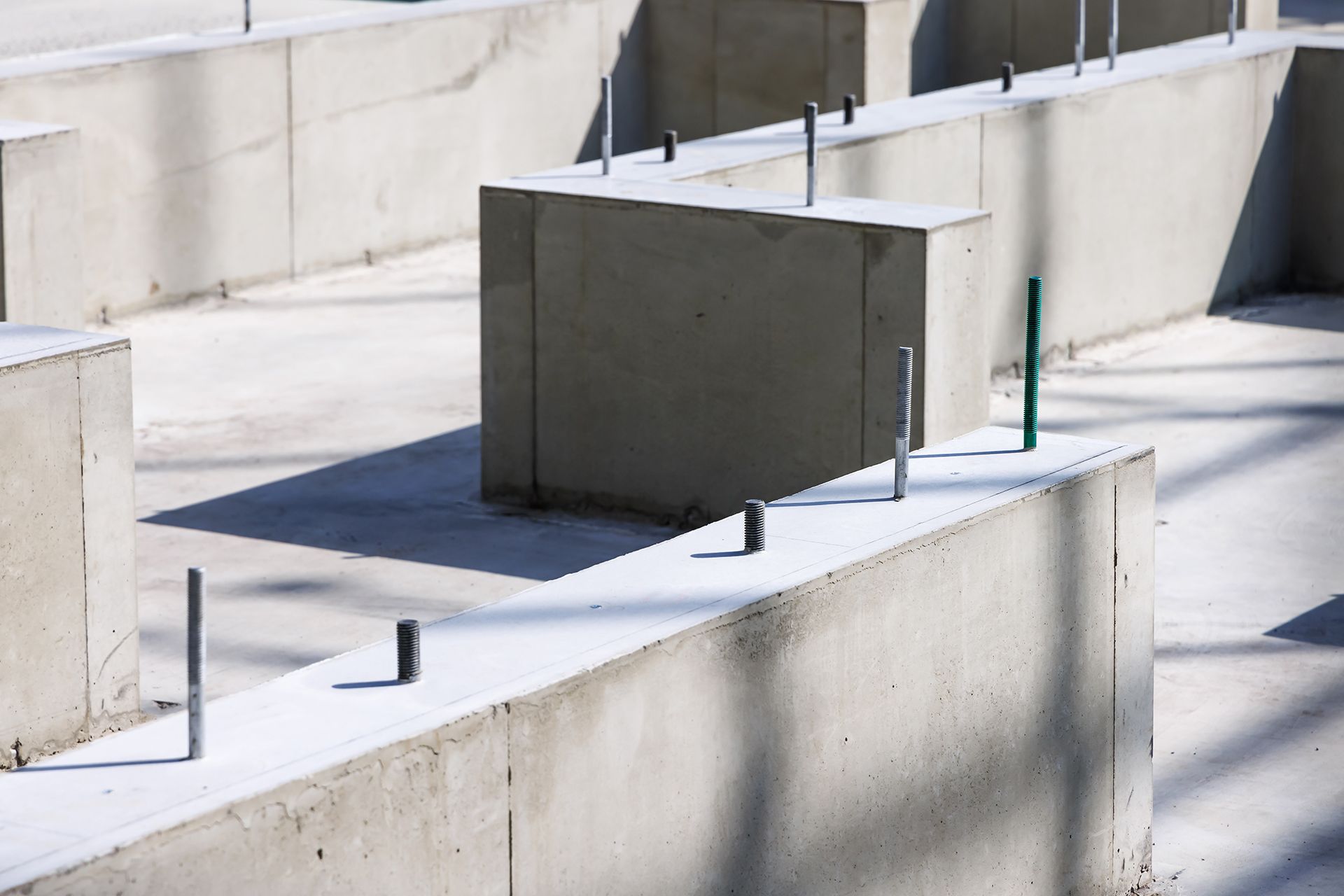 Concrete barriers and metal posts arranged in a sunlit outdoor maze.