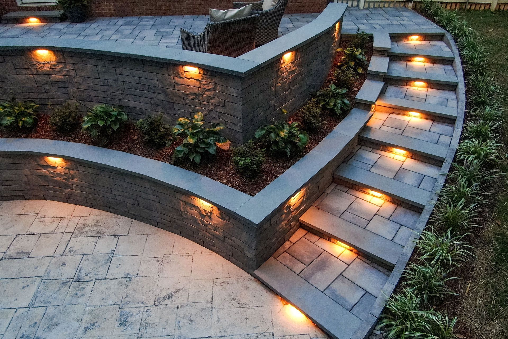 Curved stone steps and low walls with warm garden lights at dusk