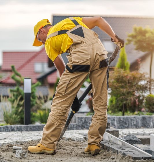 Construction worker leveling concrete with a trowel at a curbside site