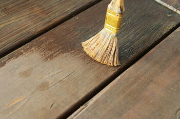 Picture of a handyman painting a wall yellow and cutting in at the baseboard.