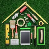 Maple Ridge Handyman picture of various tools lying on green grass forming the shape of a house.
