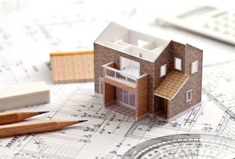 Maple Ridge Handyman 3D design model of a brown house sitting on blueprints with wood shaved pencils.