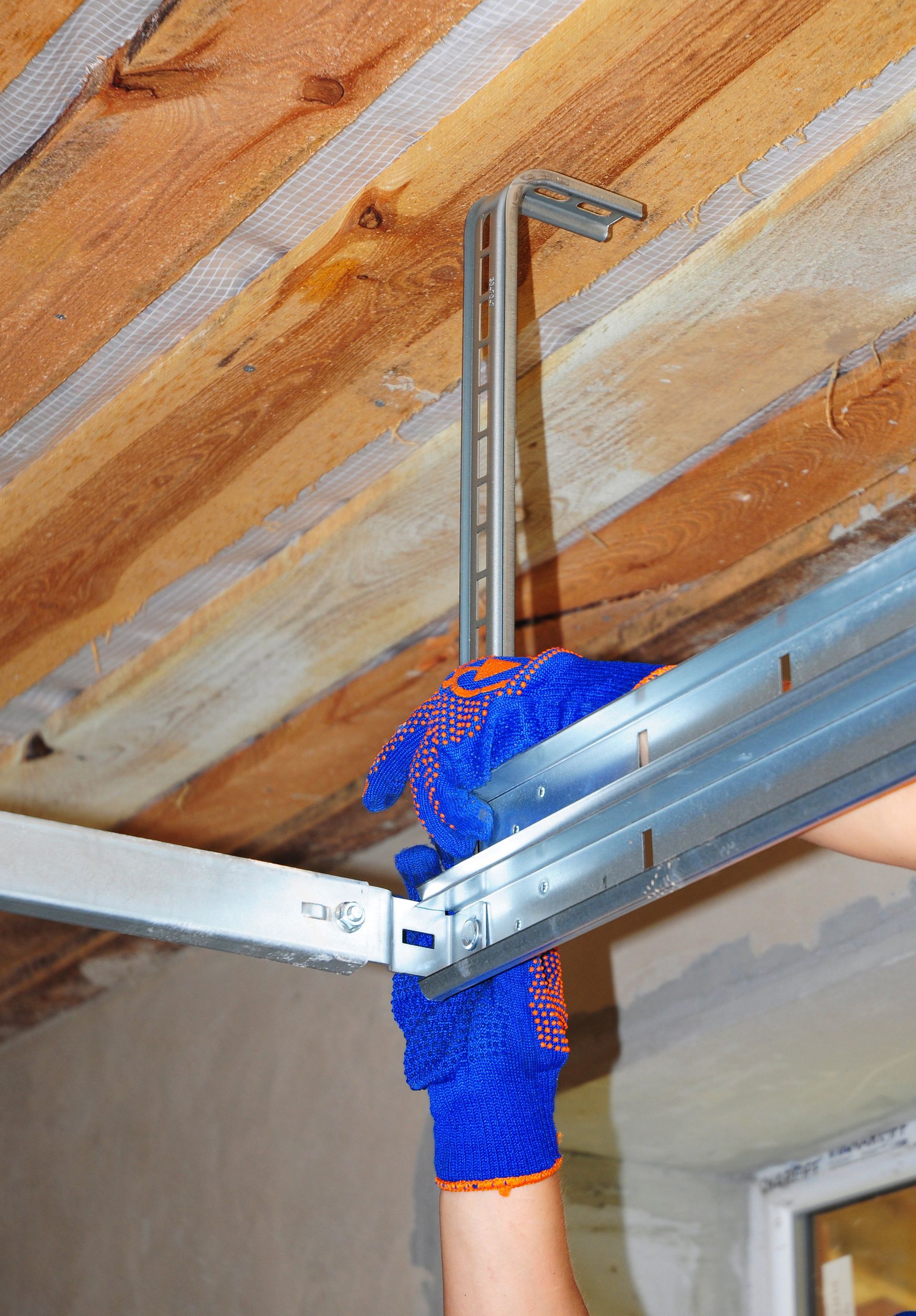 A person wearing blue gloves is working on a metal beam.