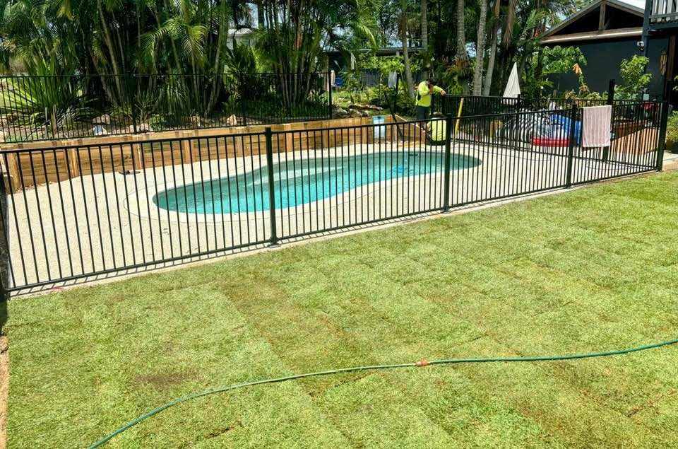 A Fence Surrounds a Swimming Pool in a Backyard — Brendan's Landscaping and Fencing In Bundaberg, QLD