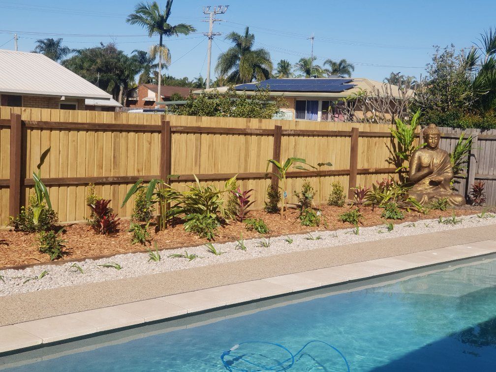 A Swimming Pool With a Wooden Fence Around It — Brendan's Landscaping and Fencing In Bundaberg, QLD