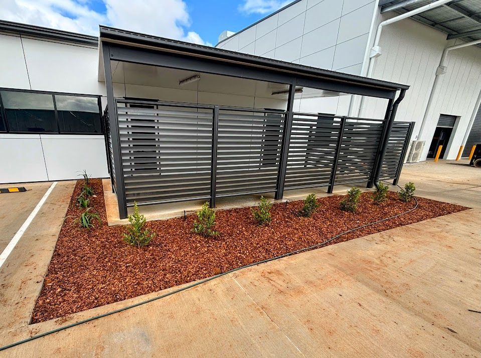 A Blue Shed With Purple Flowers in Front of It — Brendan's Landscaping and Fencing In Bundaberg, QLD