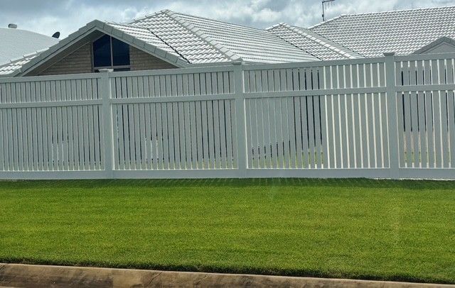 A White Fence Surrounds a Dry Grassy Field — Brendan's Landscaping and Fencing In Bundaberg, QLD