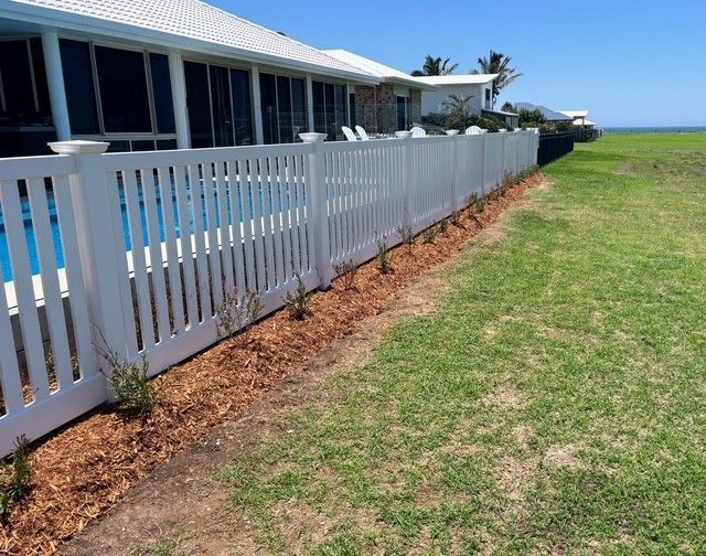 A White Fence Along a Dirt Road in a Field — Brendan's Landscaping and Fencing In Bundaberg, QLD
