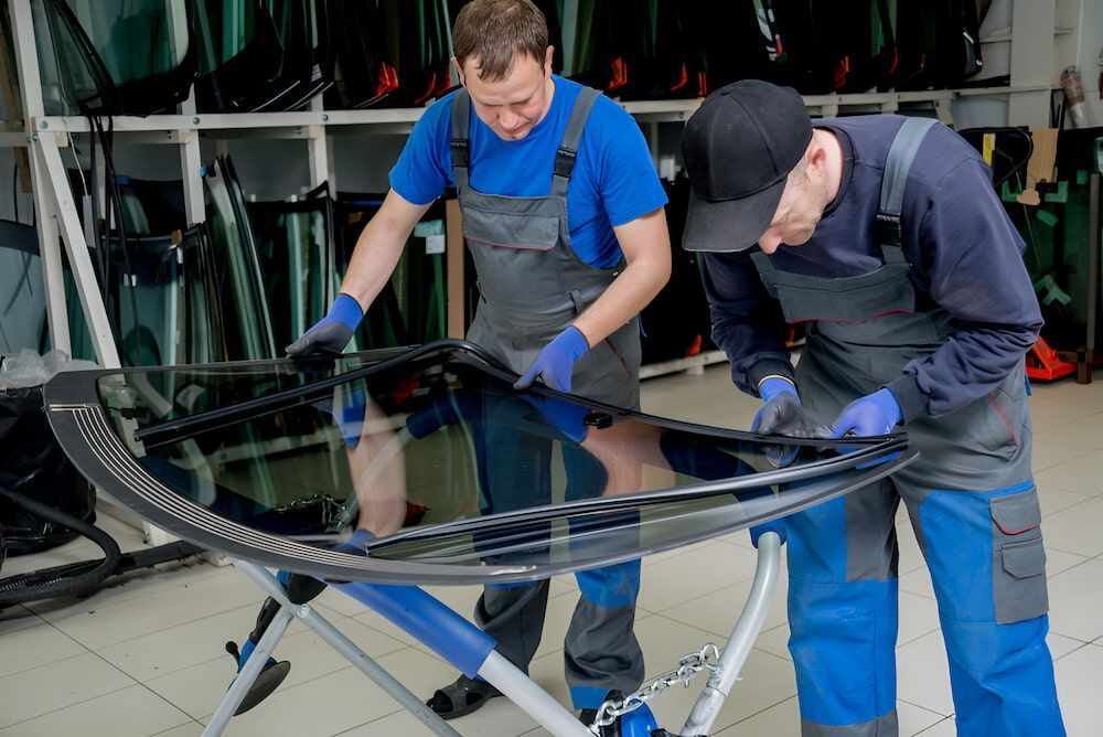 Two Men Are Working On A Windshield In A Garage — Canberra Windscreens In Conder, ACT