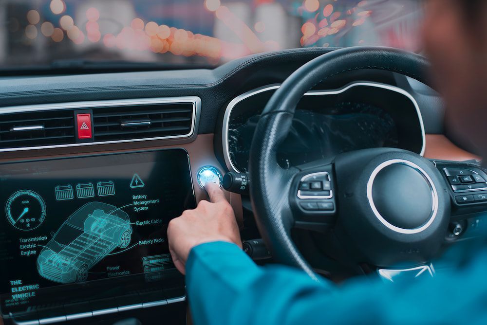 A Man Is Driving A Car And Pressing A Button On The Dashboard — Canberra Windscreens In Conder, ACT