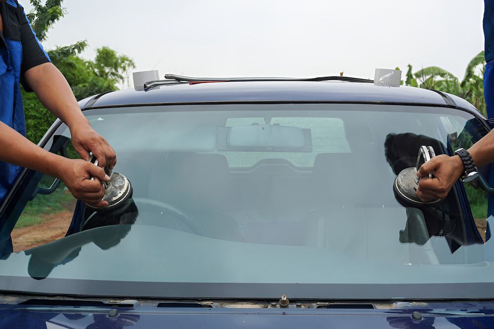 A Man Is Installing A Windshield On A Car — Canberra Windscreens In Weston Creek, ACT