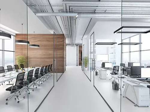 Modern open-plan office with glass walls, conference table, and rows of desks with computers