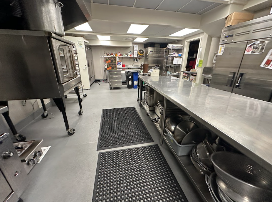 A white kitchen hutch holds a coffee machine, kettle, and microwave, with a stainless steel refrigerator to the right.