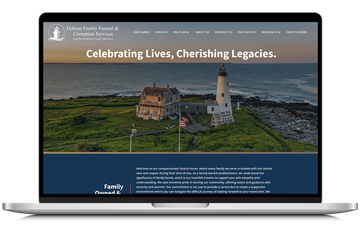 Laptop displaying a memorial website with a sunset lighthouse scene and the heading “Celebrating Lives, Cherishing Legacies.”