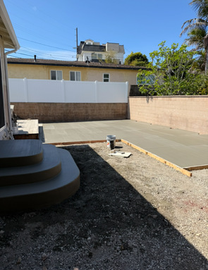 Newly poured concrete patio with surrounding brick and fence.