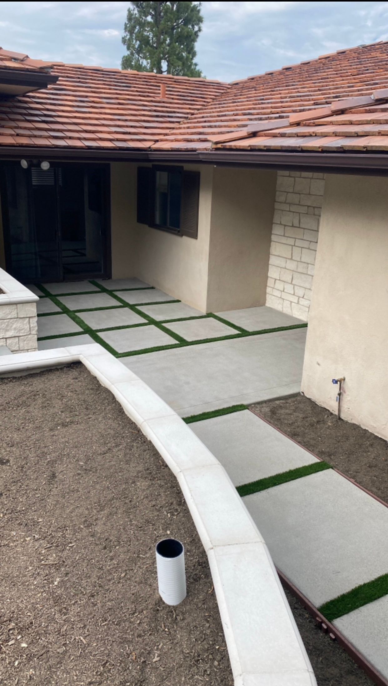 Concrete walkway leading to a home's entrance, with green artificial turf accents.
