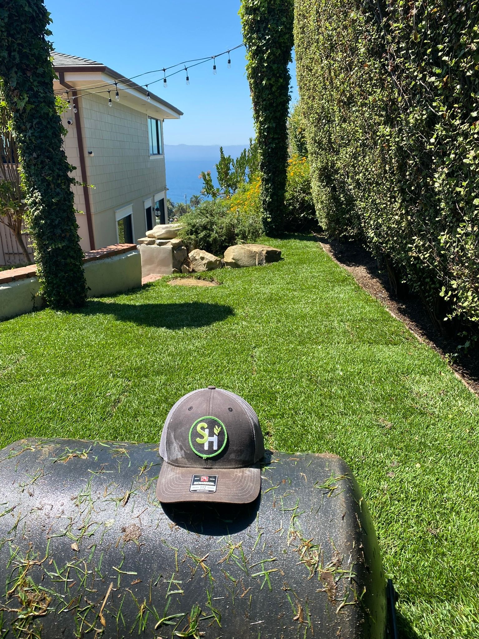 Cap on a roller, lush green lawn with ocean view.