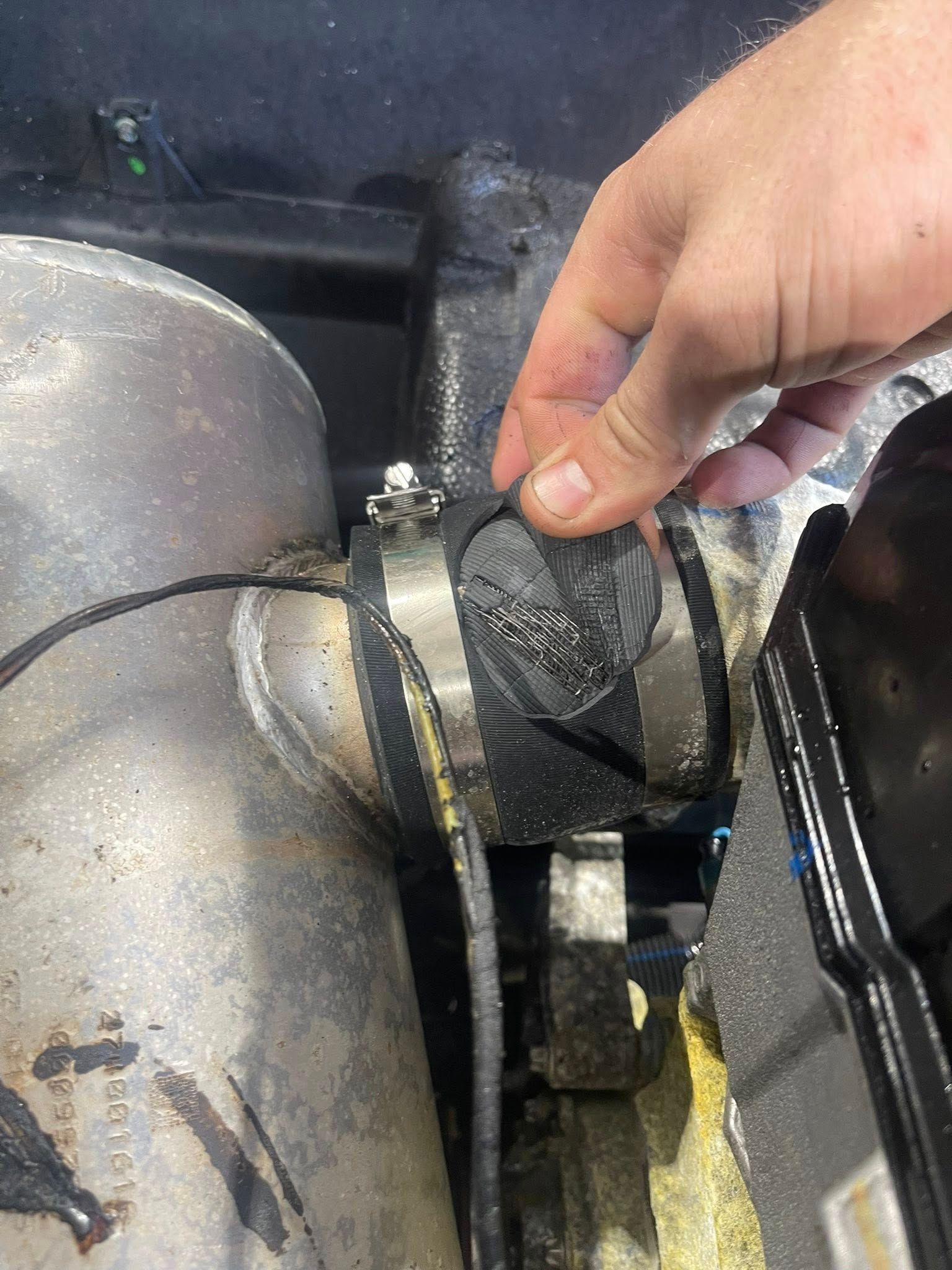 A Hand Peels a Damaged, Black Rubber Sleeve or Adhesive Repair Patch — Hastings Mobile Marine Services In Wauchope, NSW