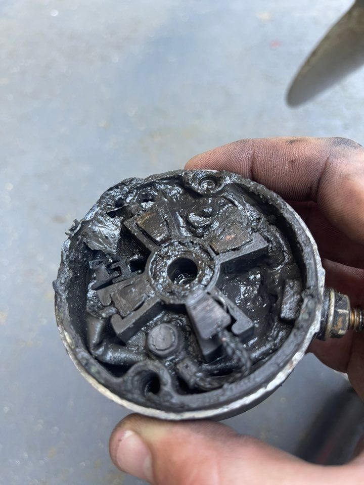 A Hand Holds a Severely Charred and Melted Electric Motor — Hastings Mobile Marine Services In Laurieton, NSW