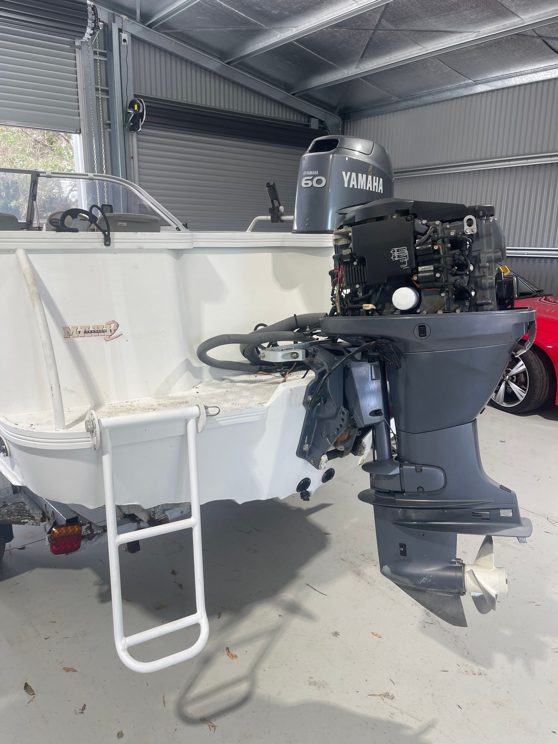 A White Boat With an Exposed Outboard Motor Parked in a Garage — Hastings Mobile Marine Services In Wauchope, NSW