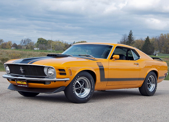 A yellow mustang is parked on the side of the road