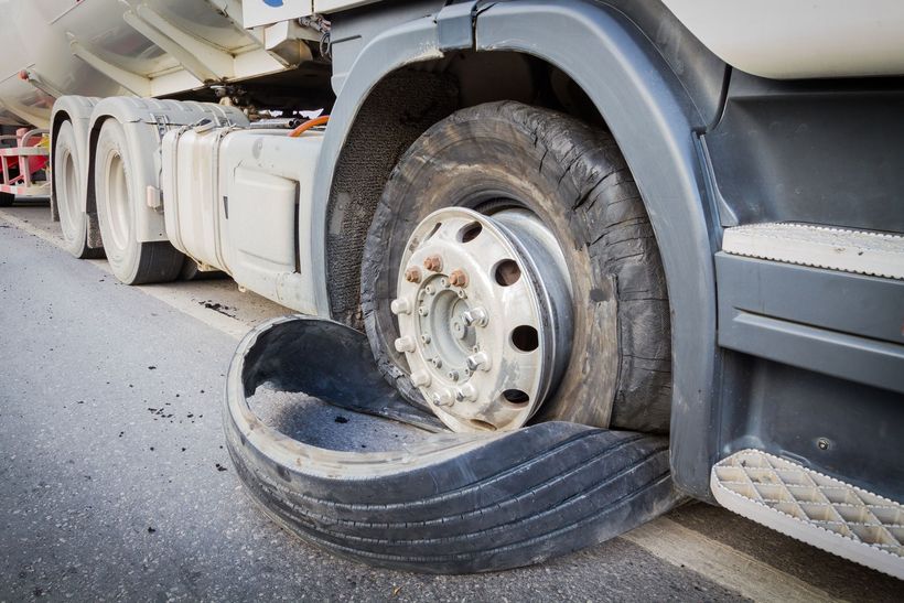 A truck with a flat tire on the side of it.