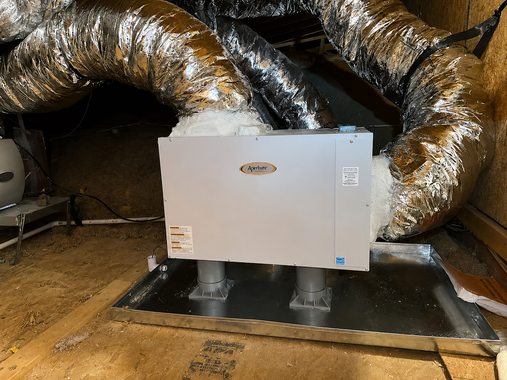 Gray ventilation unit with silver ducts in a utility room on a black platform