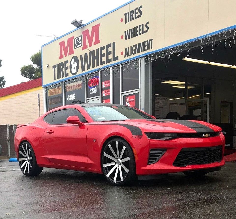 Red and black car in front of M & M tire and wheel shop
