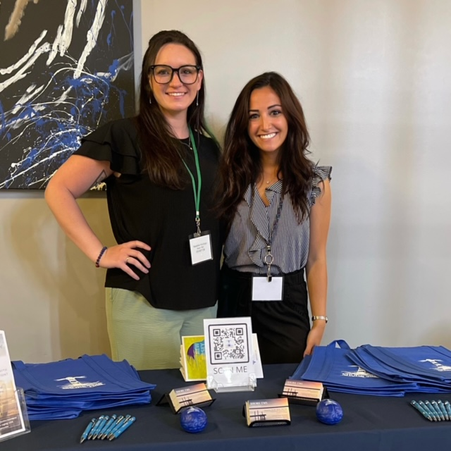 Two women standing next to each other in front of a table