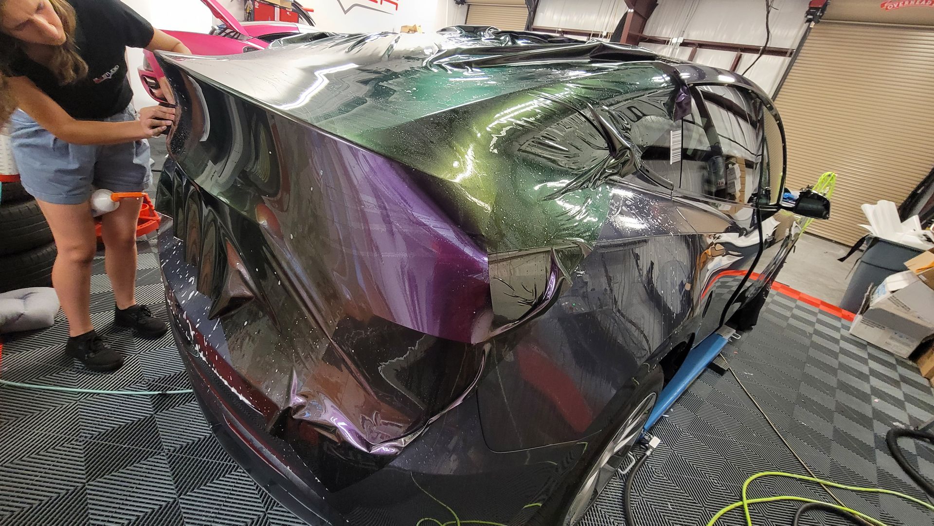 A blue and purple sports car is sitting on a lift in a garage.
