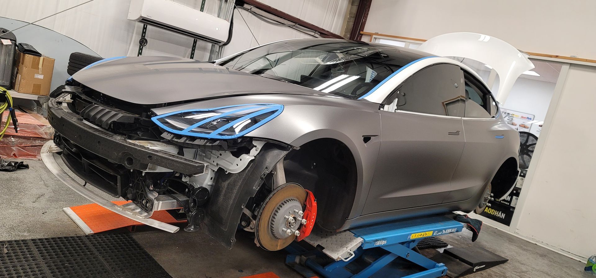 A blue car is being wrapped in blue plastic.