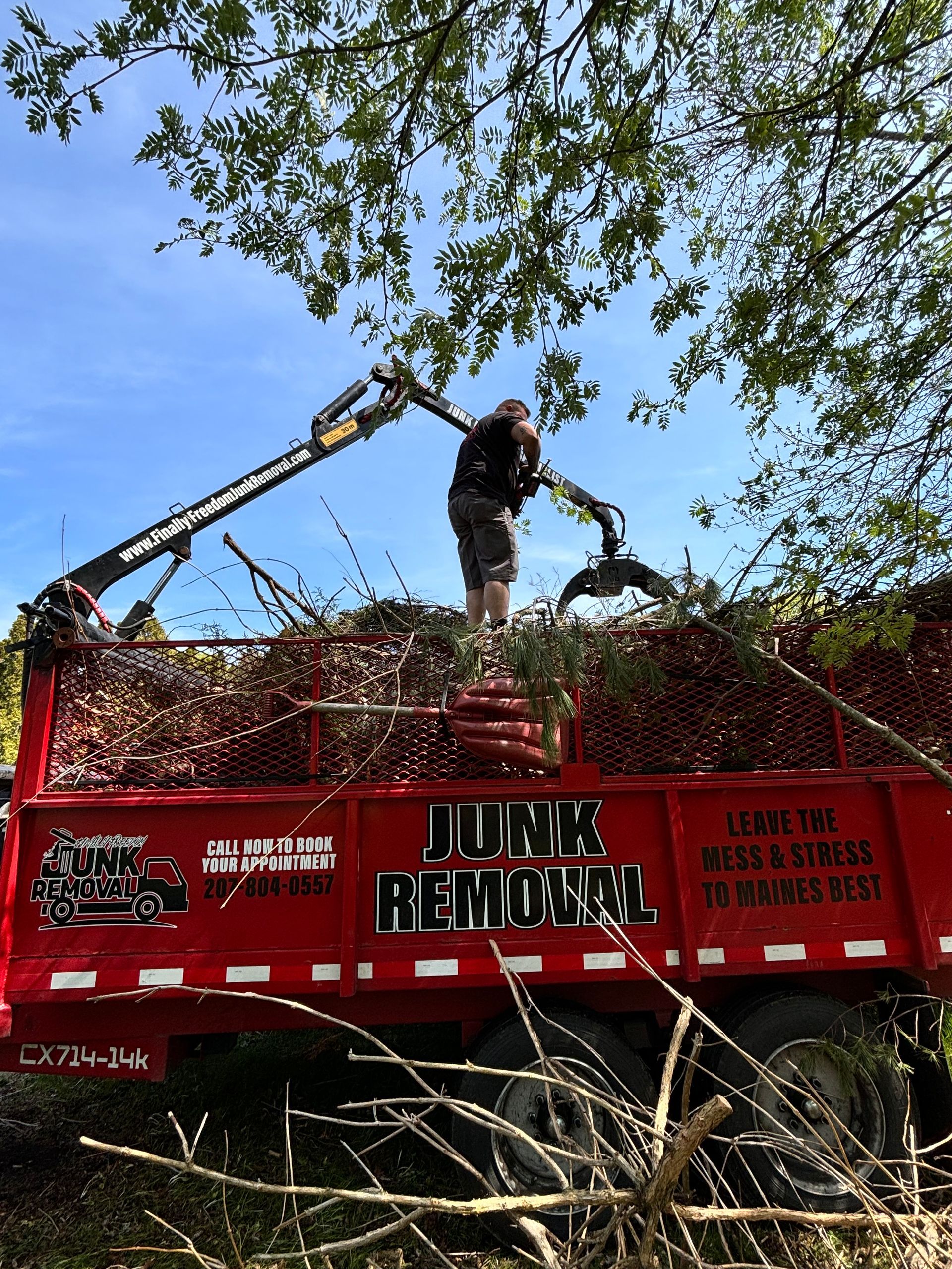 Finally Freedom Junk Removal loading brush into their truck bed with their crane