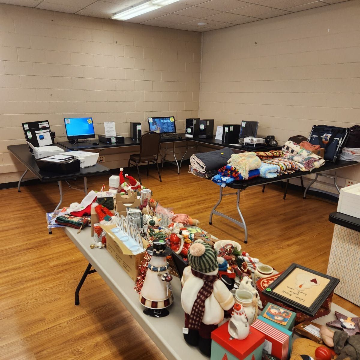 Room with tables displaying Christmas decor and computers; likely a sale or event.