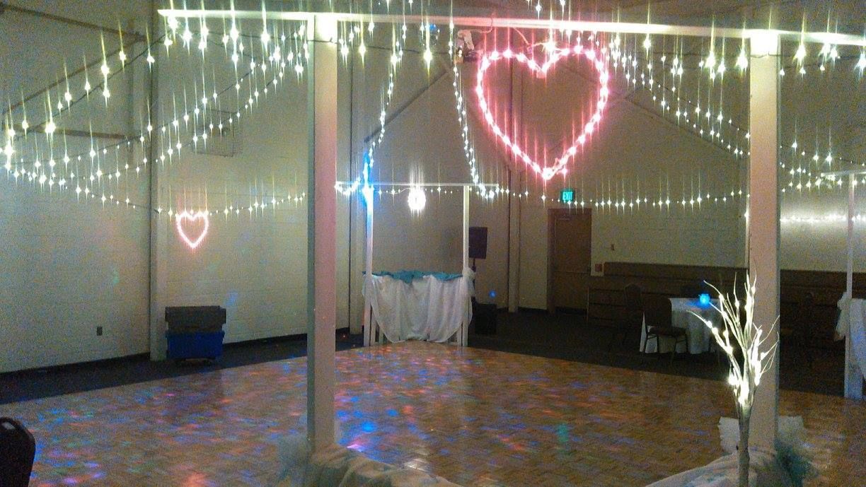 Wedding reception hall with string lights, heart-shaped lights, and decorated dance floor.