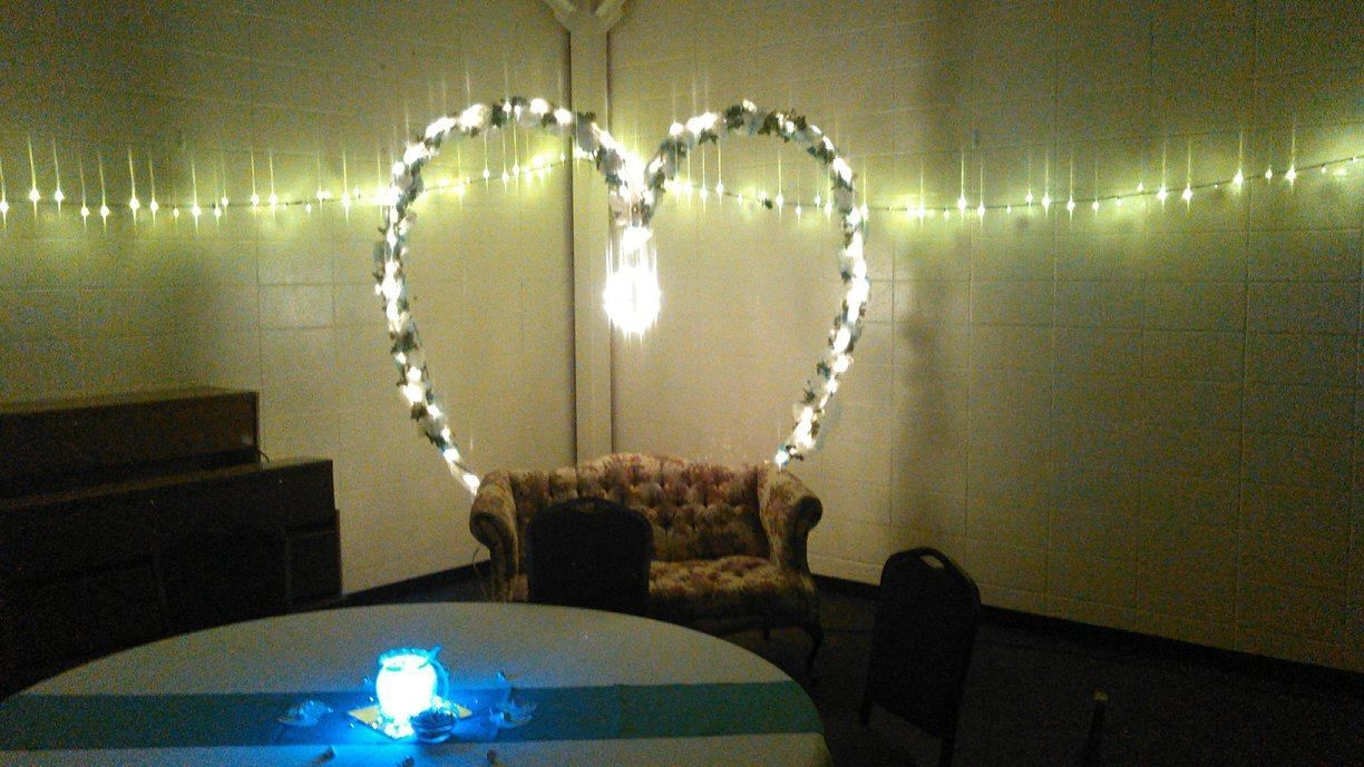 A glowing heart-shaped light arch frames a vintage sofa in a room with fairy lights; a table is in the foreground.