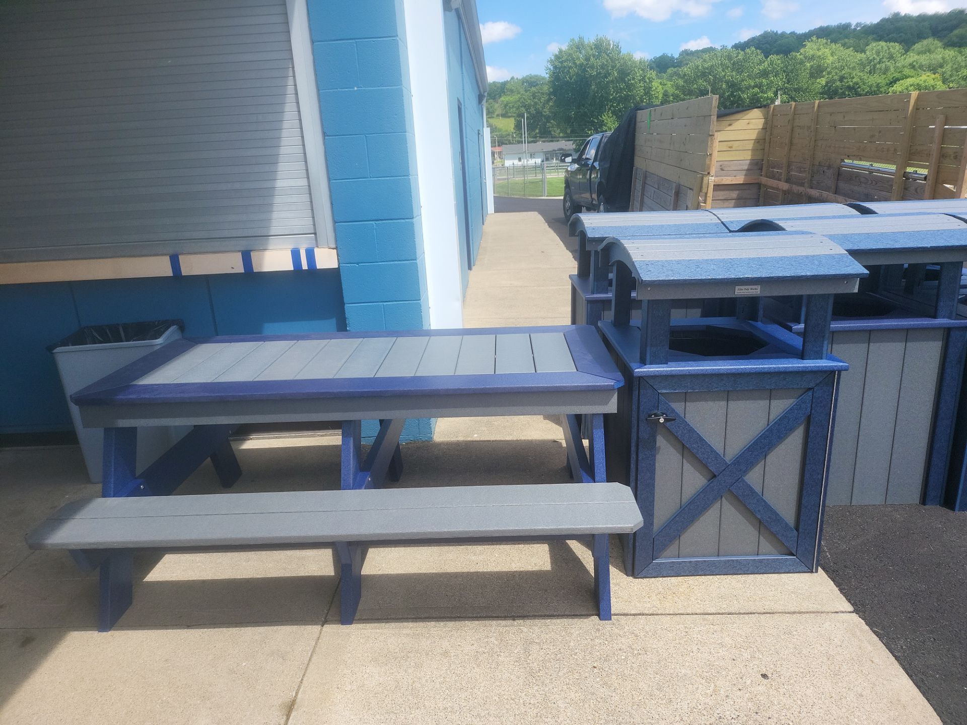 A picnic table with a bench and a trash can