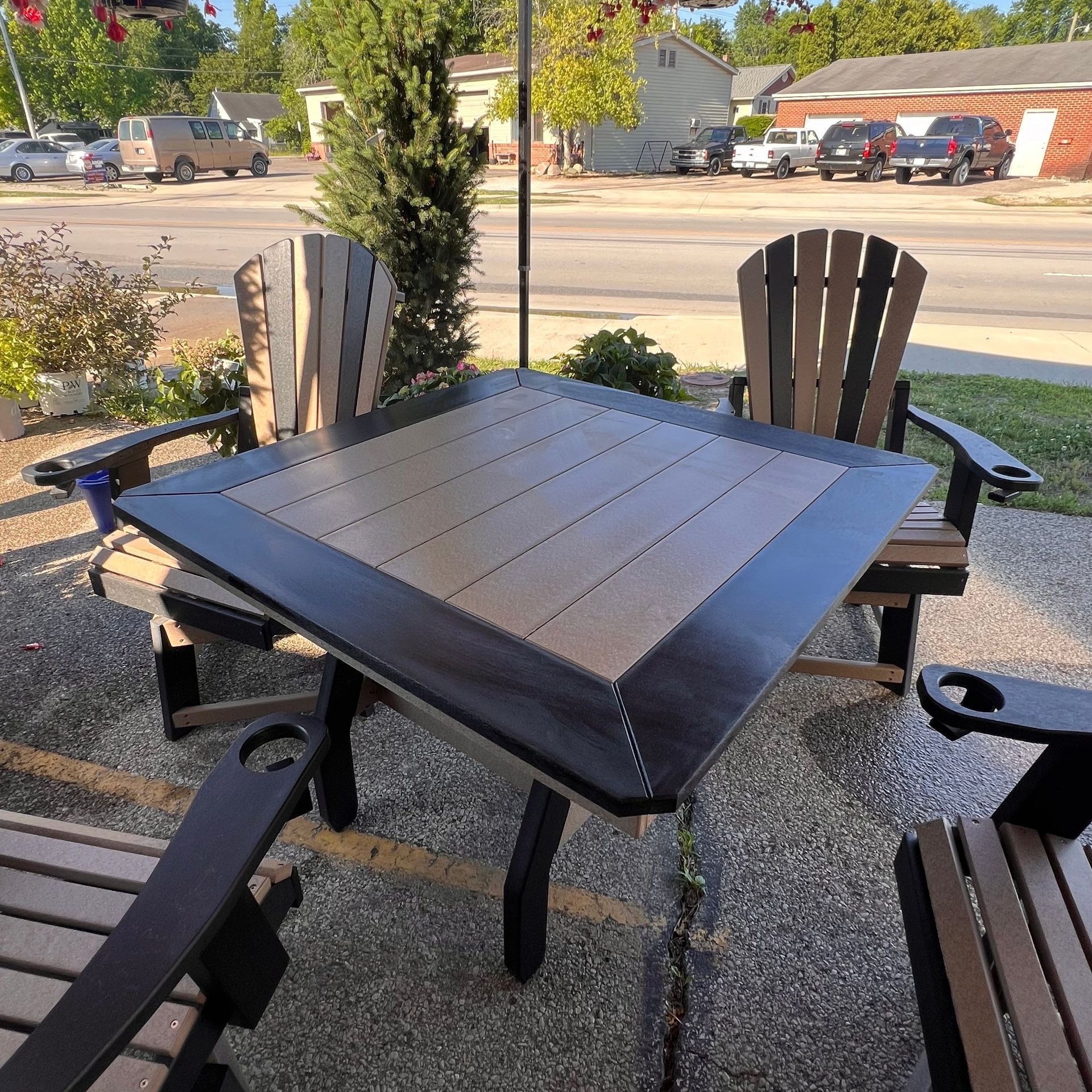 A table and chairs on a patio with cars parked in the background