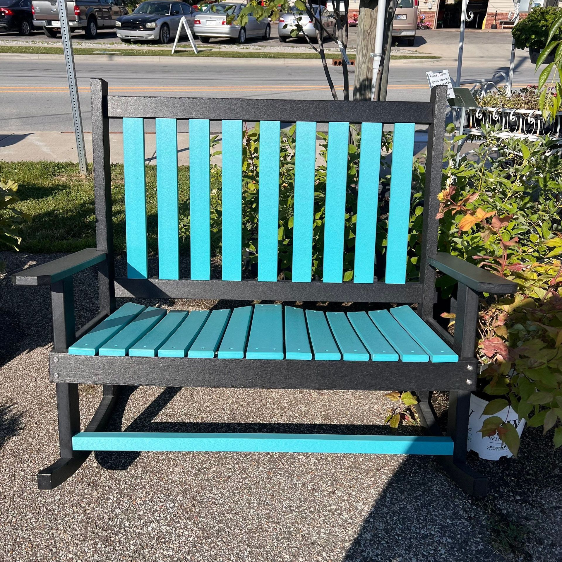 A black and blue porch swing is sitting on the sidewalk.