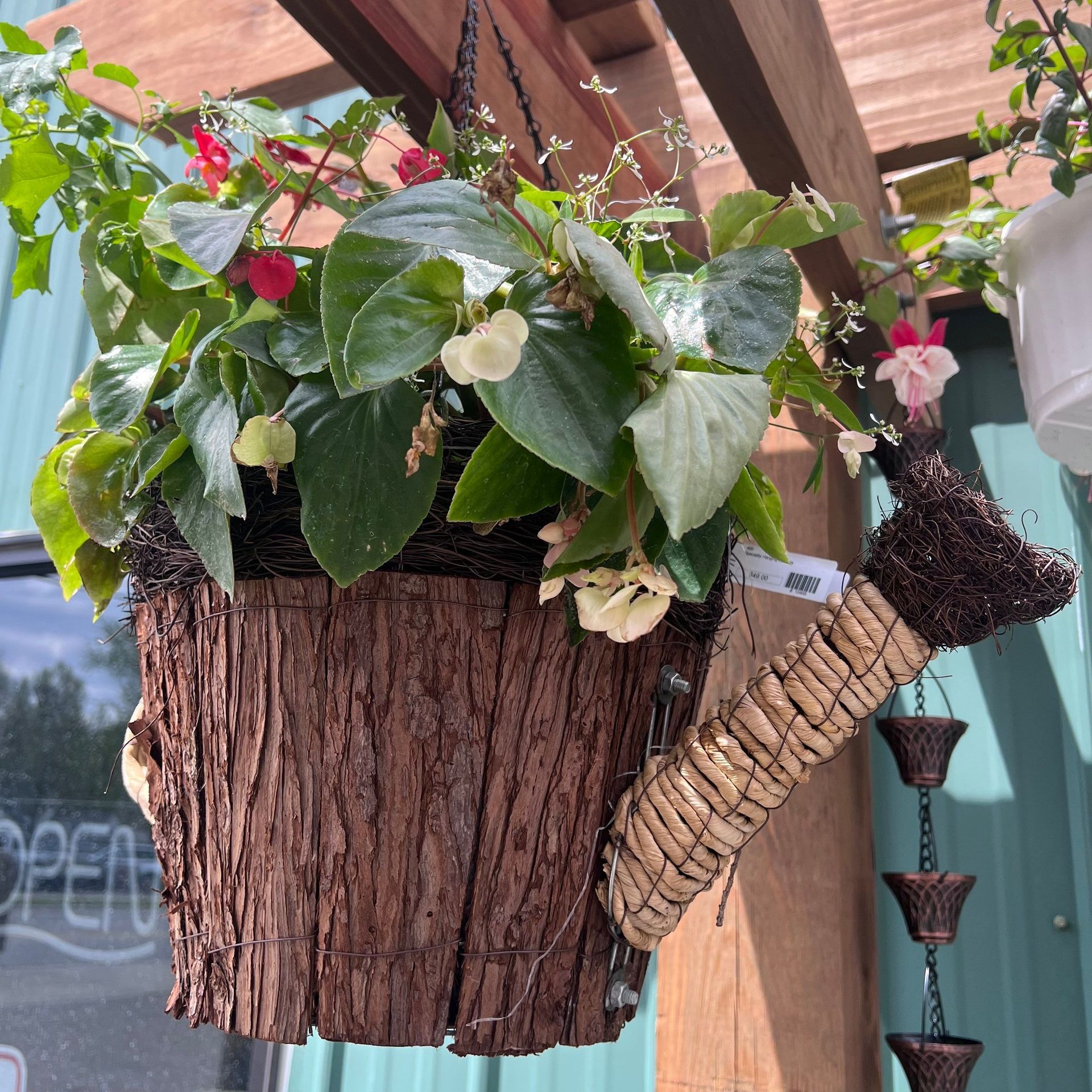 A hanging basket filled with flowers is hanging from a wooden structure.