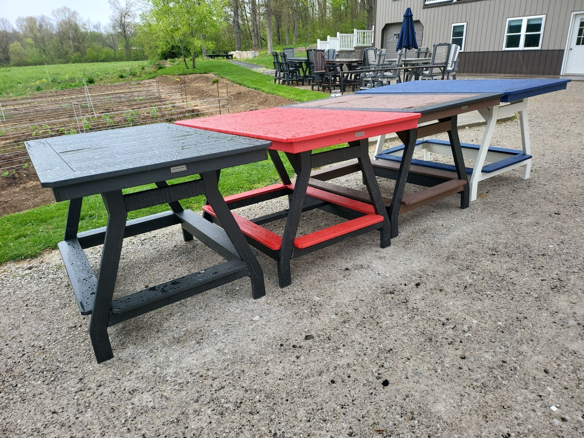 A row of colorful picnic tables are lined up on a gravel road.