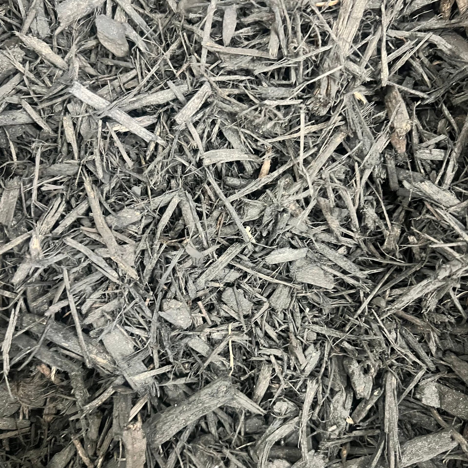 A pile of gray mulch is sitting on the ground.