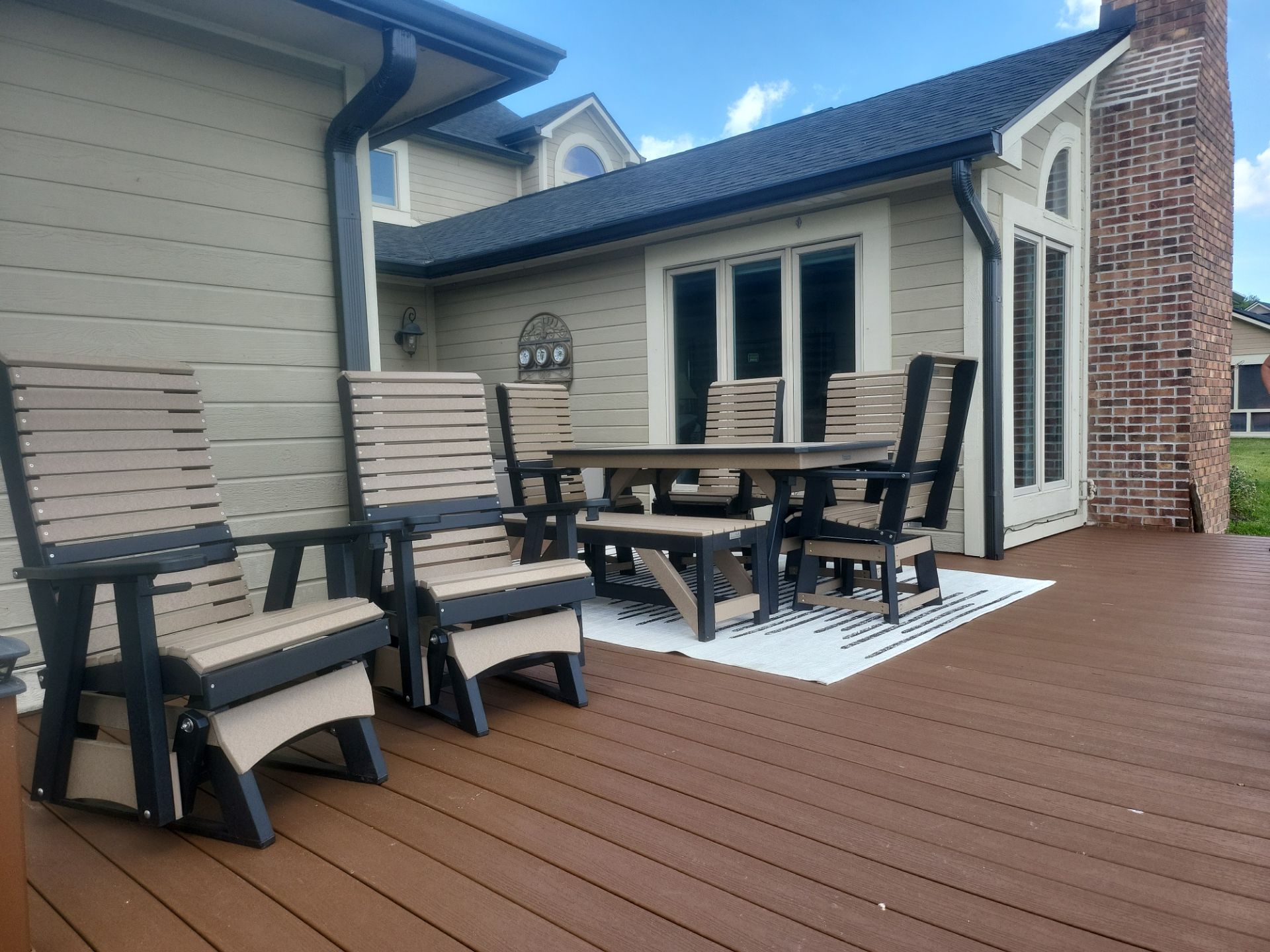A deck with chairs and a table in front of a house.