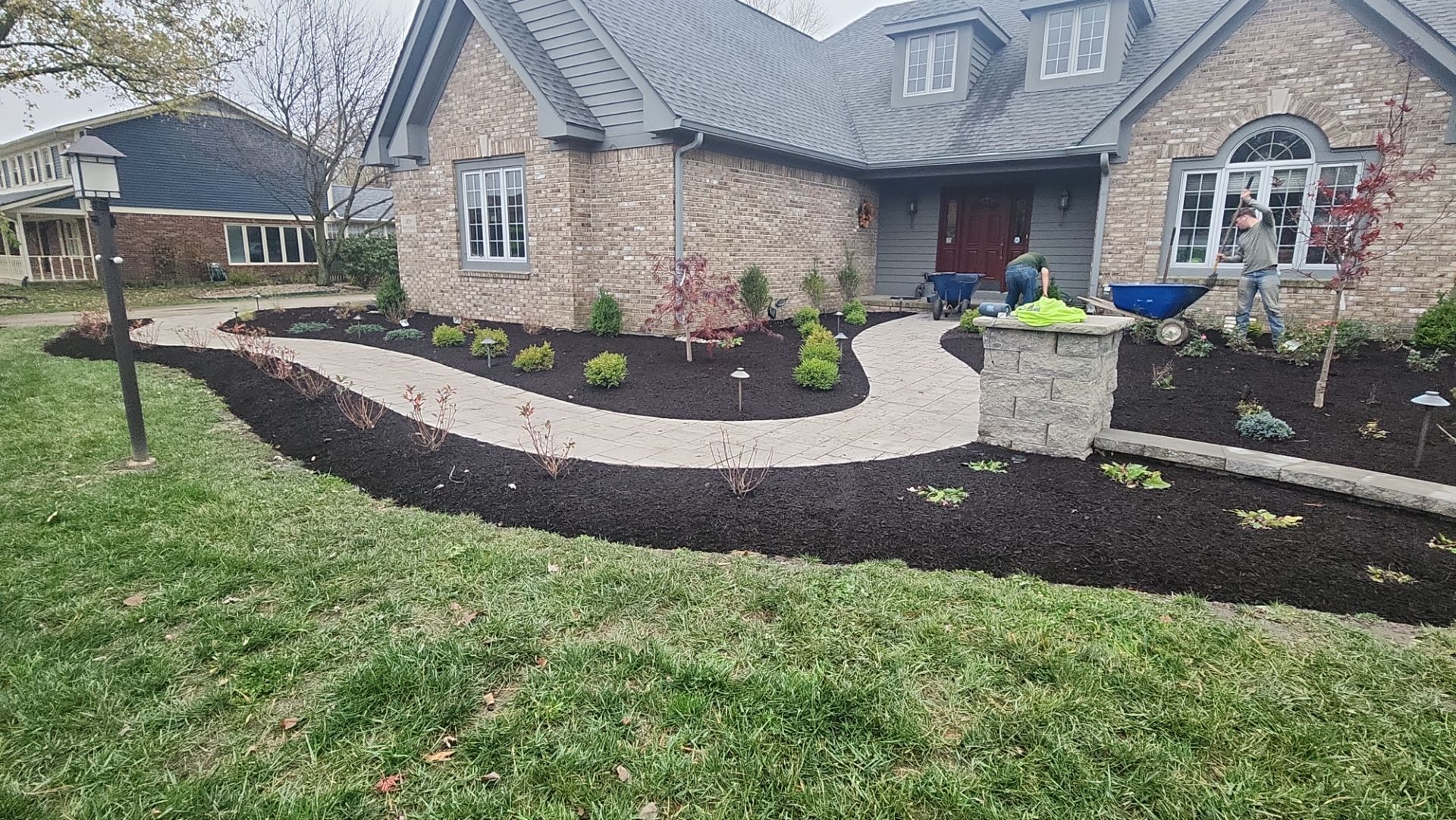 A brick house with a walkway and mulch in front of it.