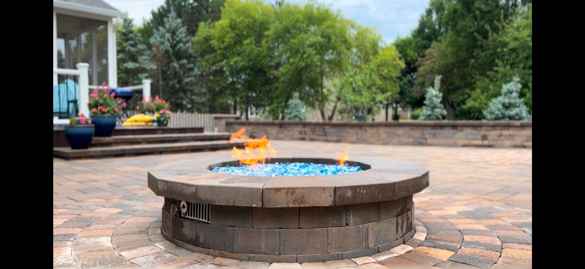 A fire pit is sitting on top of a patio next to a house.