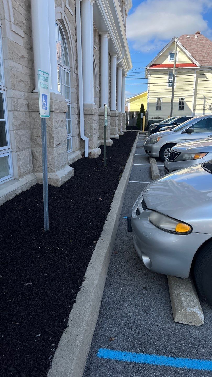 A row of cars are parked in a parking lot in front of a building.
