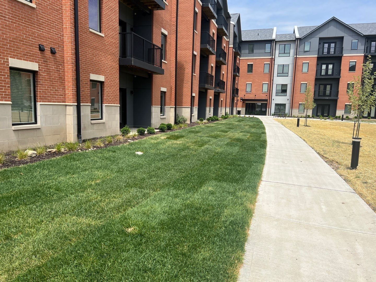 A brick apartment building with a concrete walkway leading to it.