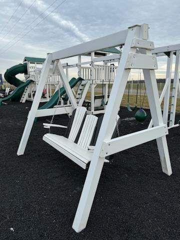 A white swing set is sitting in the middle of a playground.