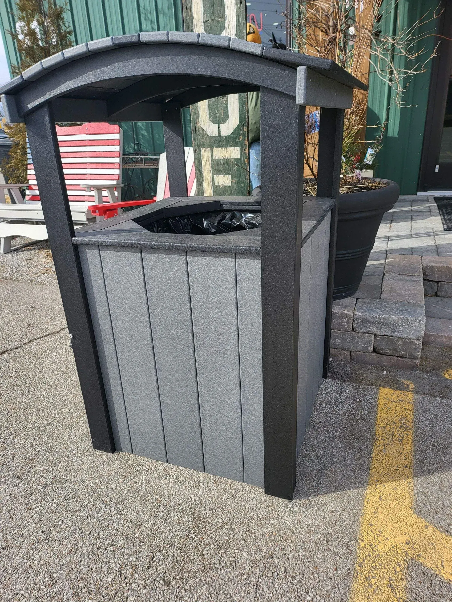A trash can is sitting on the ground in a parking lot.
